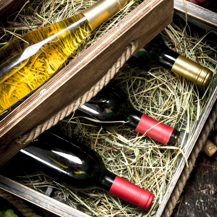 Wine background. Bottles of red and white wine in old boxes. On a wooden background.