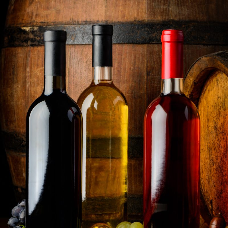 Tree bottles of wine in a vintage wine cellar. Red, white and rose wine on wooden background